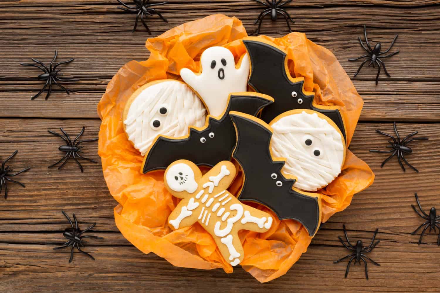 Halloween cookies with bats and ghosts on wood.