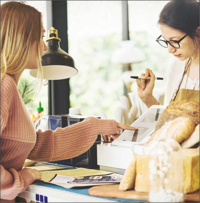 Two women discussing over documents in a bakery