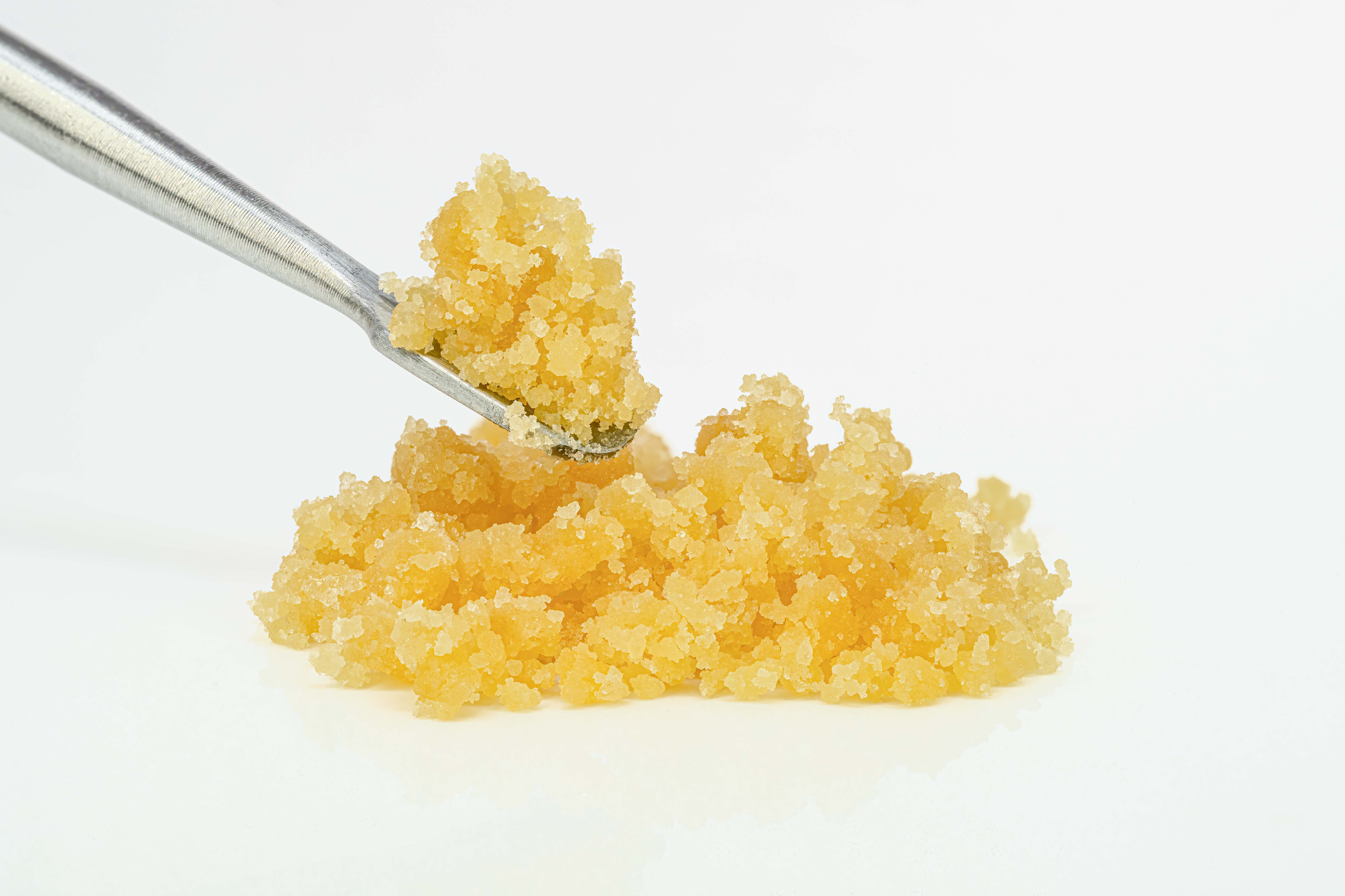 Tweezers picking up amber-colored granulated sugar