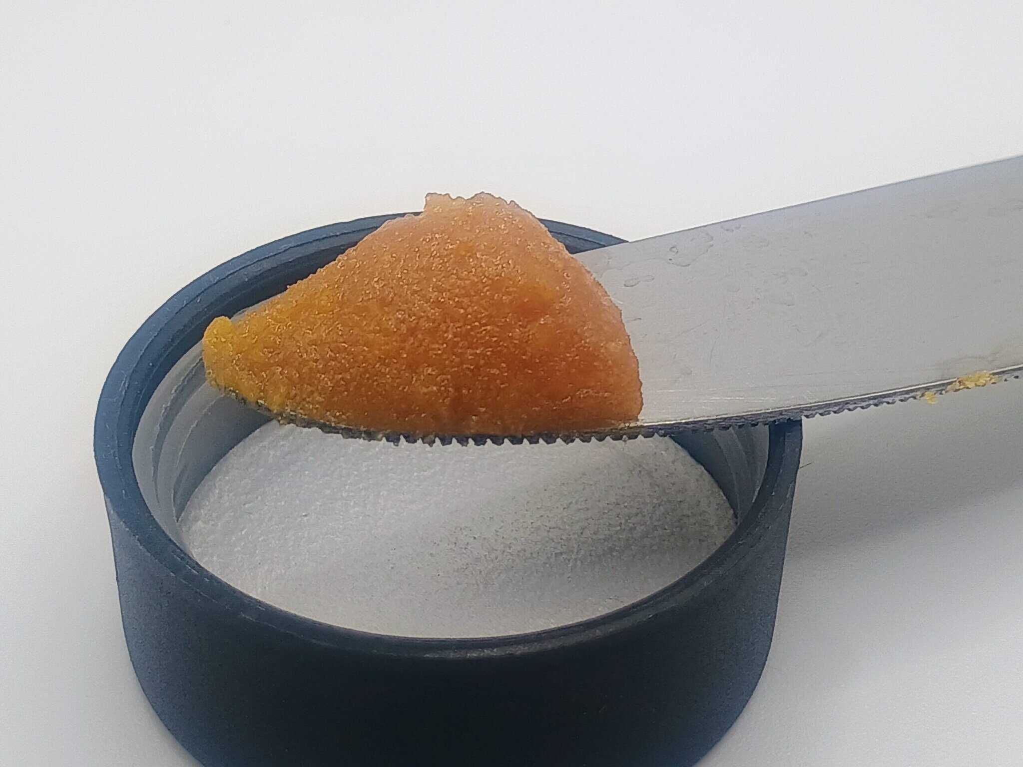Knife spreading orange substance on container