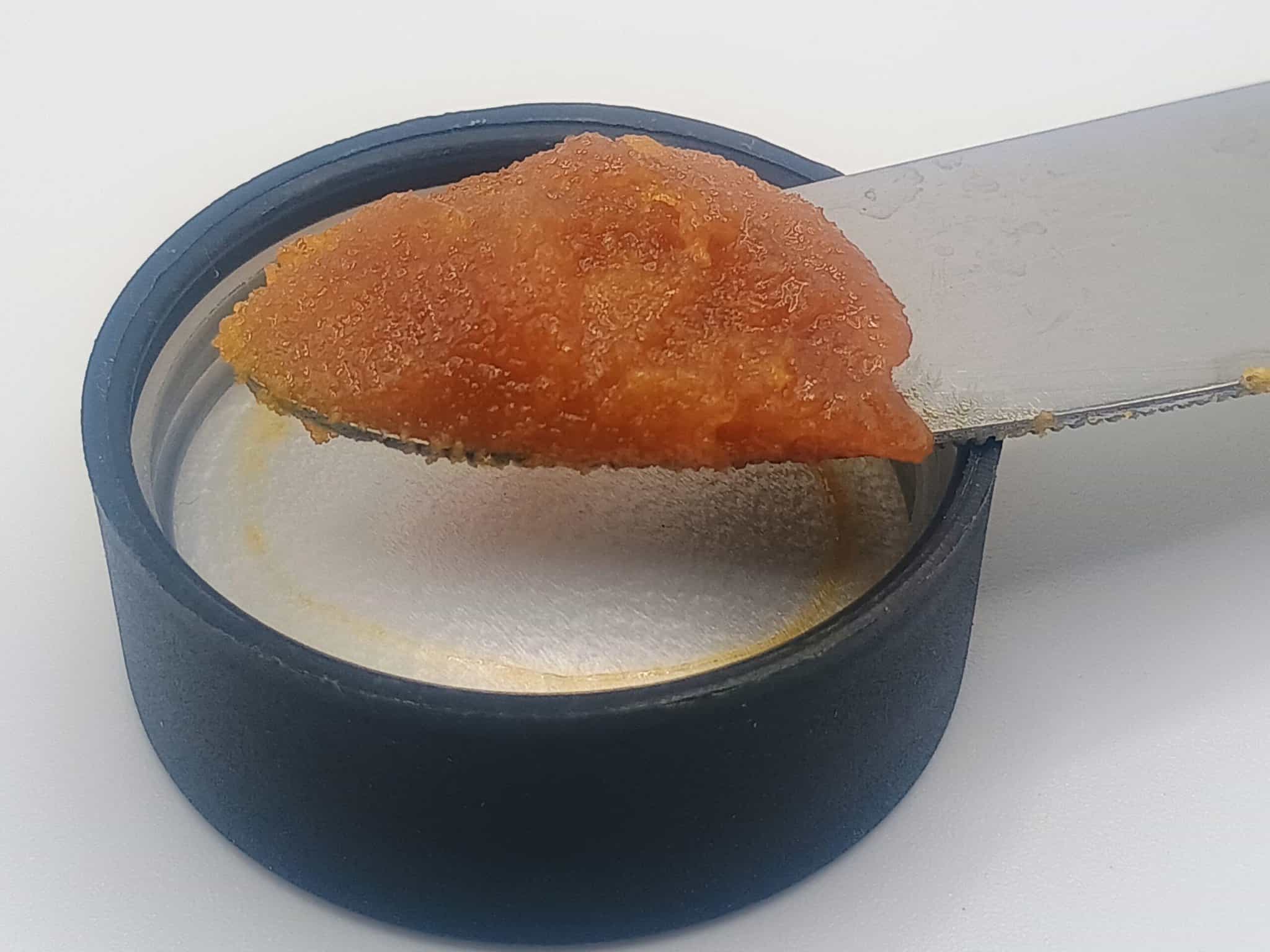 Orange paste on knife over container