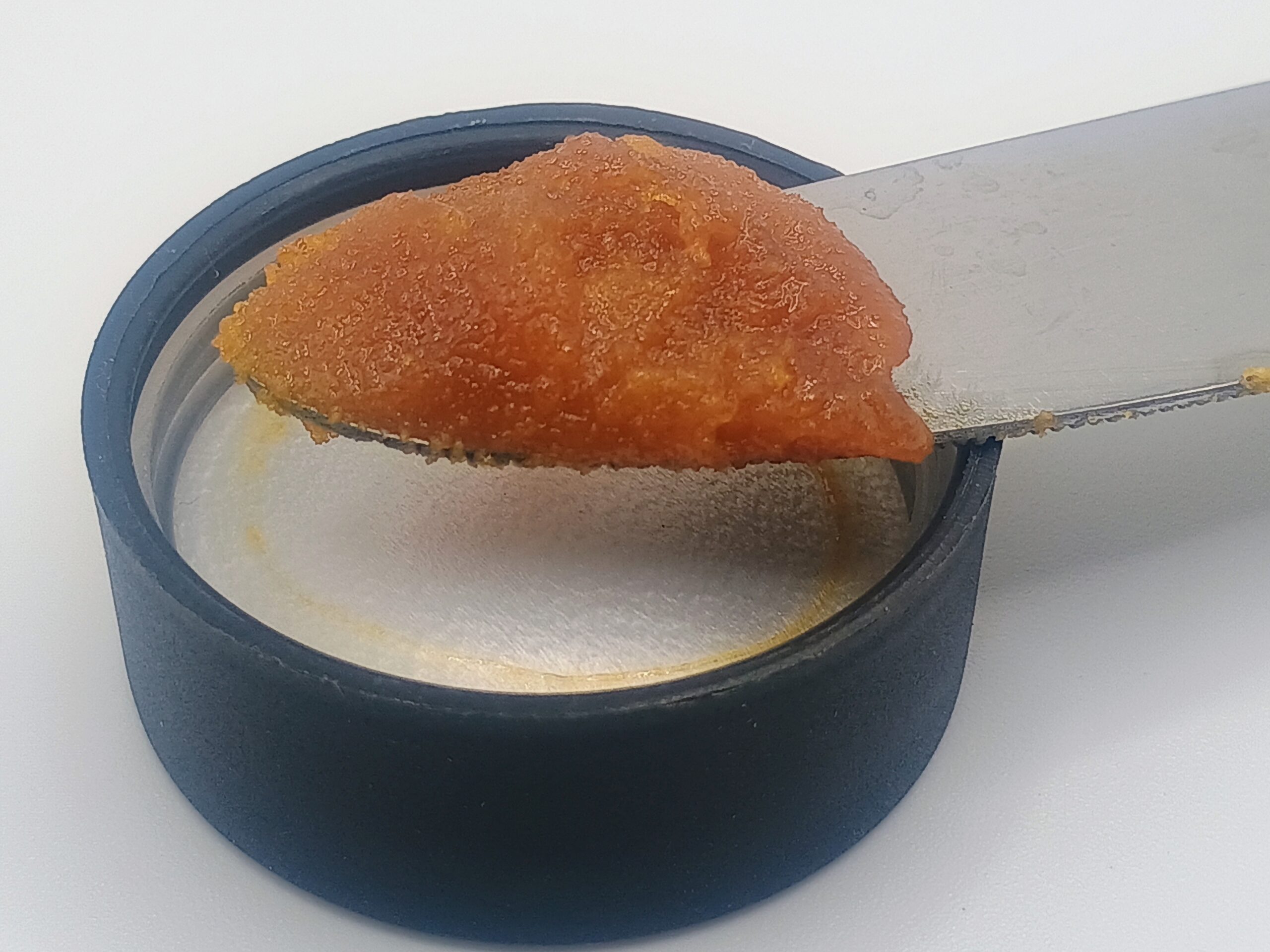 Knife spreading tomato paste on jar lid